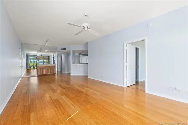 a view of empty room with wooden floor and fan