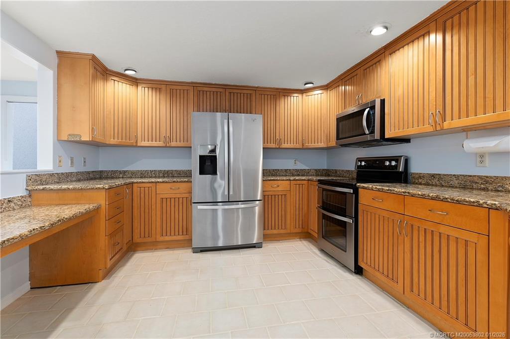 6122 Southeast Landing Way, Unit 4 Stuart, FL 34997 - Photo 3 of 23 a kitchen with a refrigerator a stove a sink dishwasher and wooden cabinets