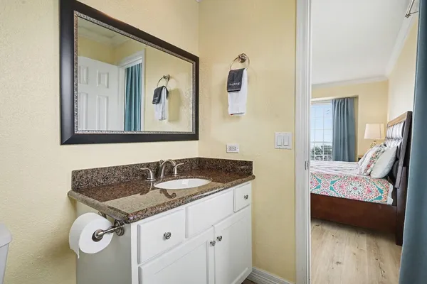 a en suite bathroom with a granite countertop sink and a mirror