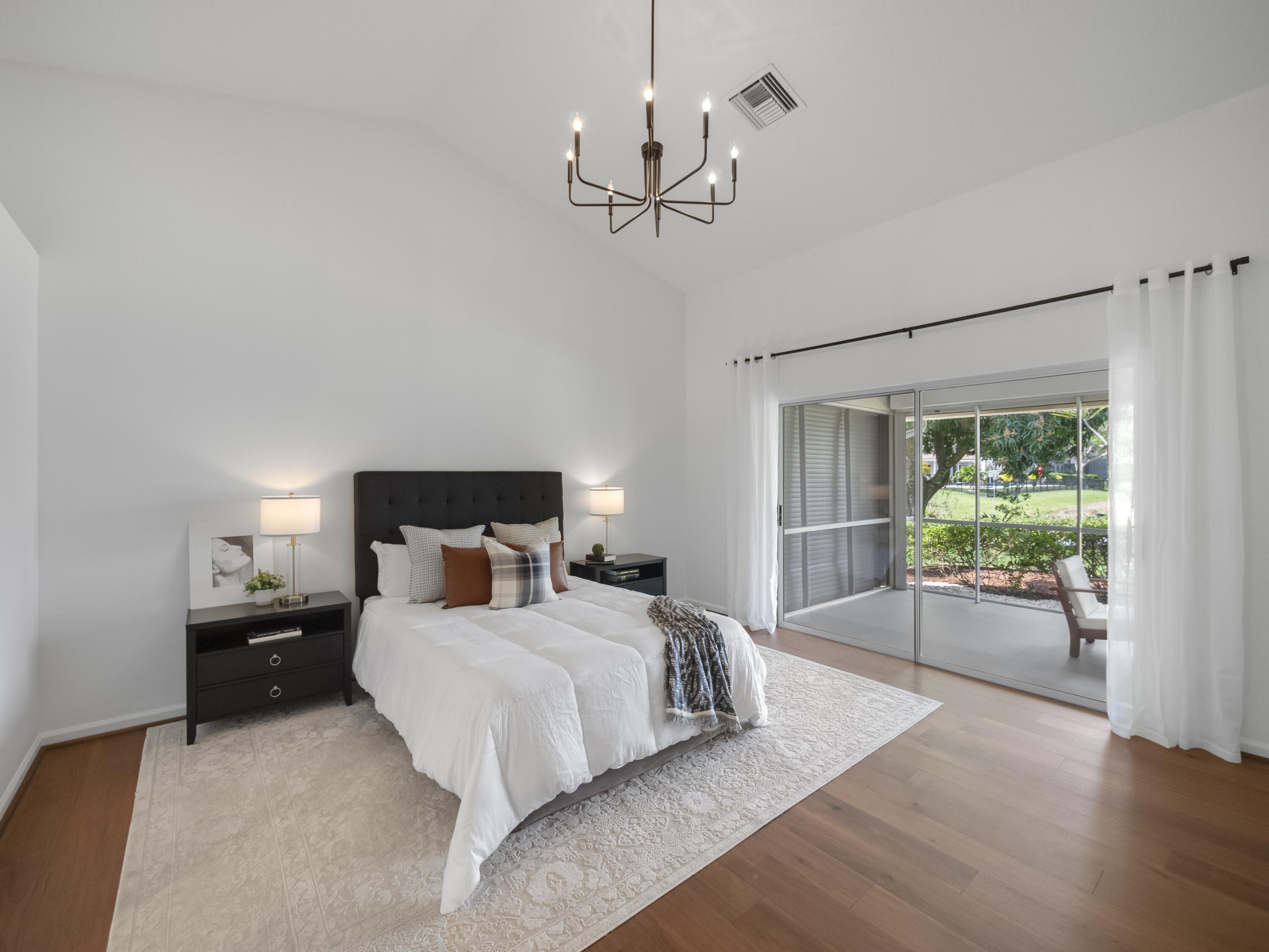 6279 Longleaf Pine Drive Jupiter, FL 33458 - Photo 10 of 33 a large bedroom with a bed and a chandelier