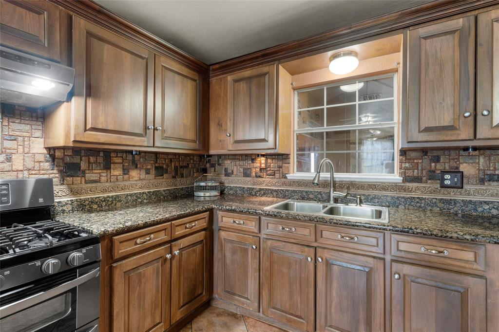 3433 West Tours Road West, TX 76691 - Photo 16 of 40 Kitchen featuring stainless steel range with gas cooktop, backsplash, under cabinet range hood, and dark stone counters