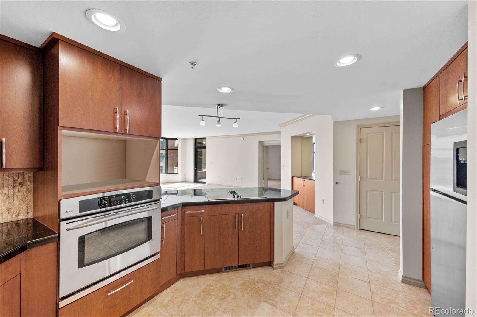 8100 East Union Avenue, Unit 814 Denver, CO 80237 - Photo 11 of 38 a kitchen with kitchen island granite countertop wooden cabinets and stainless steel appliances