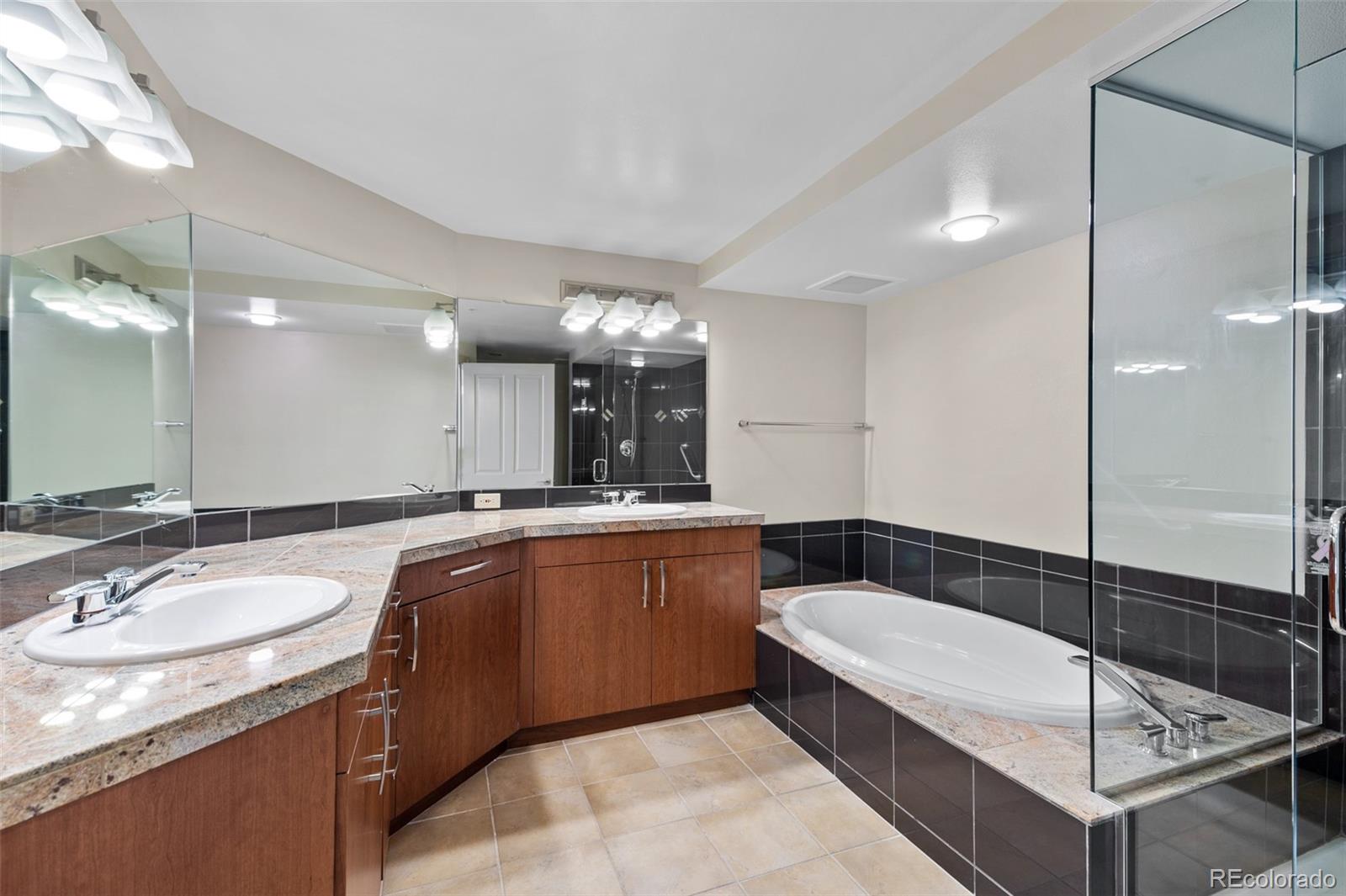 8100 East Union Avenue, Unit 814 Denver, CO 80237 - Photo 21 of 38 a bathroom with a granite countertop sink mirror and bathtub