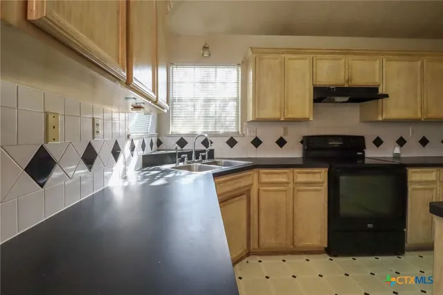 a kitchen with stainless steel appliances a sink a stove a refrigerator a sink a counter space and cabinets