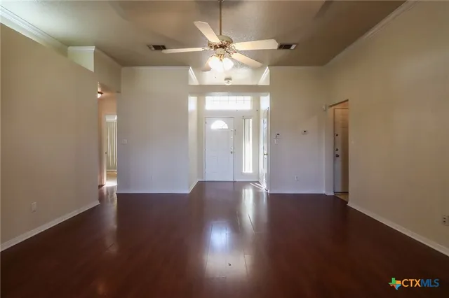 a view of an empty room with wooden floor and a window