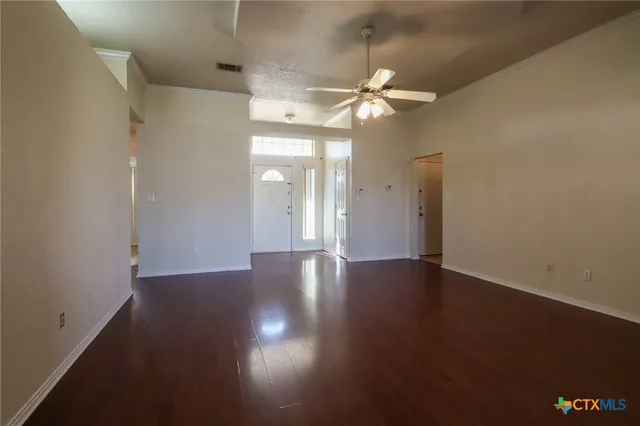 an empty room with wooden floor and windows