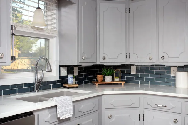a kitchen with granite countertop a sink white cabinets and a window