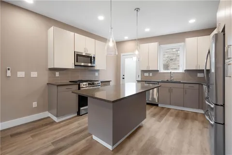 a large kitchen with stainless steel appliances granite countertop a stove a sink and a refrigerator