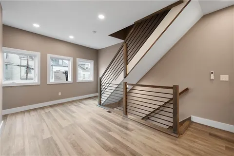 a view of an empty room with wooden floor and stairs