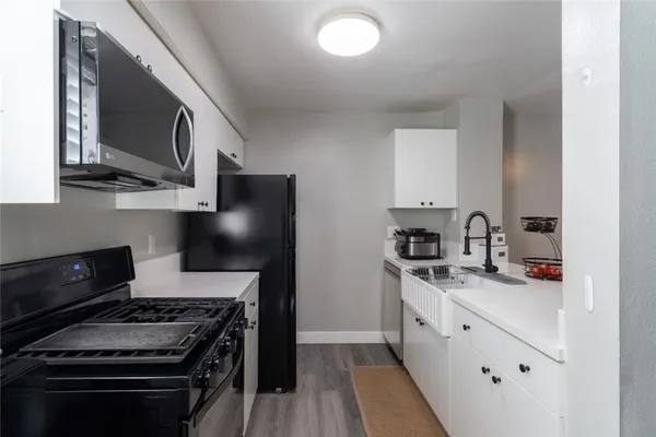 a kitchen with stainless steel appliances granite countertop a stove a sink and a microwave