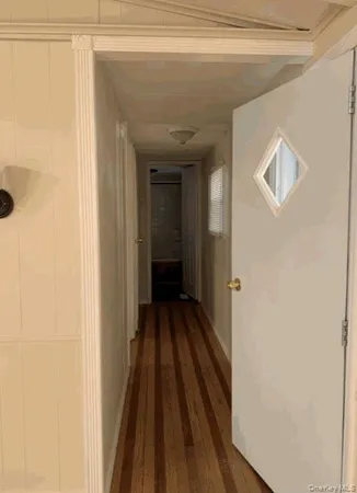 a view of a hallway with wooden floor and a bathroom