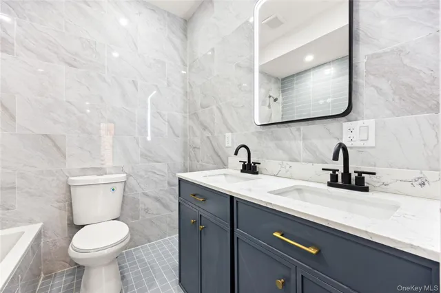 a bathroom with a granite countertop toilet sink and mirror