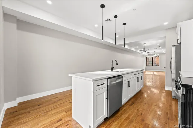 a kitchen with stainless steel appliances granite countertop a refrigerator a stove top oven a sink and dishwasher with wooden floor