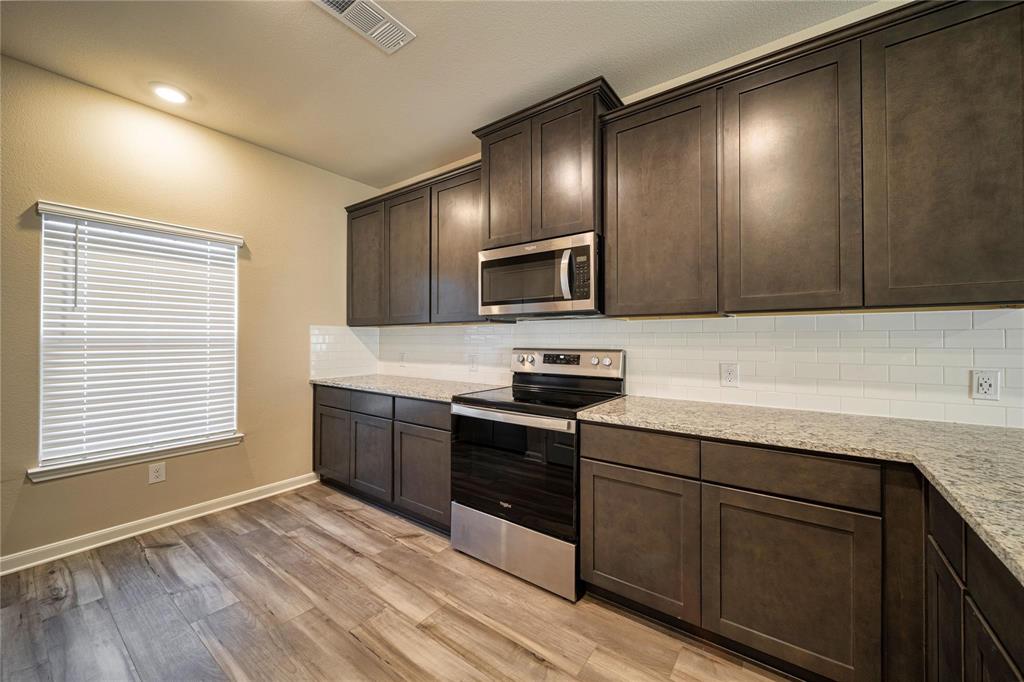 274 Honeysuckle Lane Princeton, TX 75407 - Photo 5 of 35 Kitchen featuring stainless steel appliances, backsplash, dark brown cabinetry, light stone counters, and vaulted ceiling