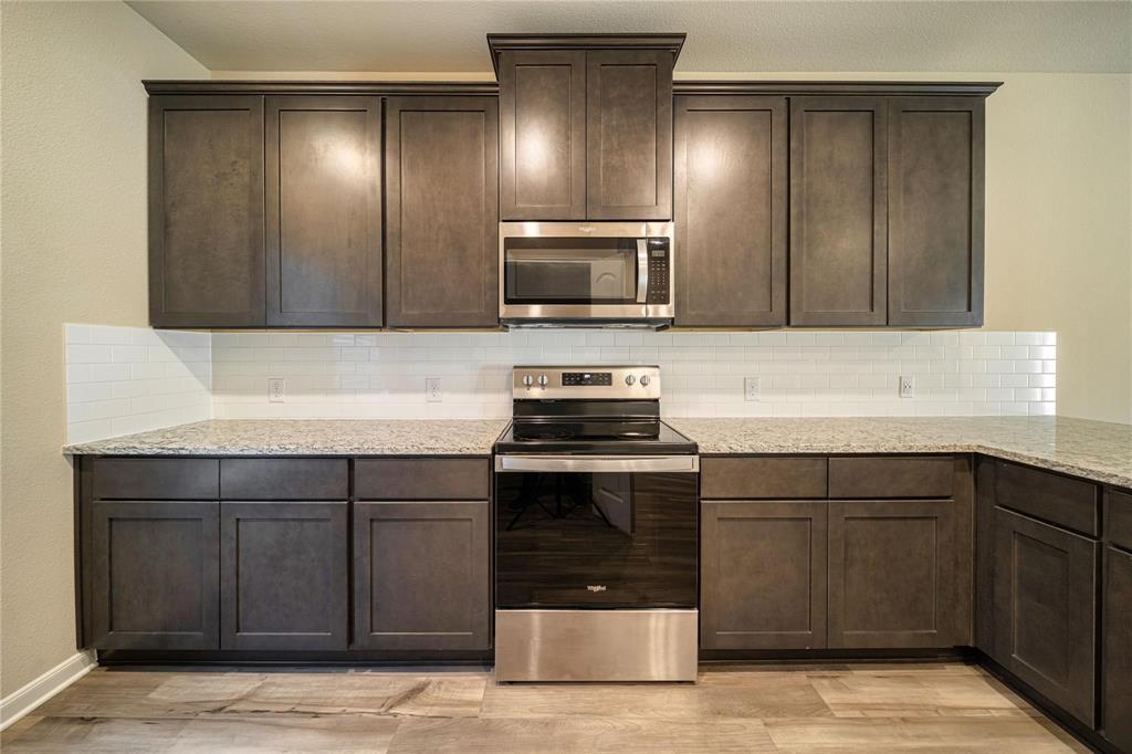 274 Honeysuckle Lane Princeton, TX 75407 - Photo 6 of 35 Kitchen featuring appliances with stainless steel finishes, light stone counters, dark brown cabinets, and backsplash