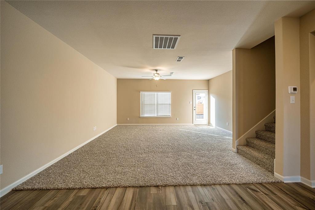 274 Honeysuckle Lane Princeton, TX 75407 - Photo 8 of 35 Carpeted empty room with stairway, a ceiling fan, and wood finished floors