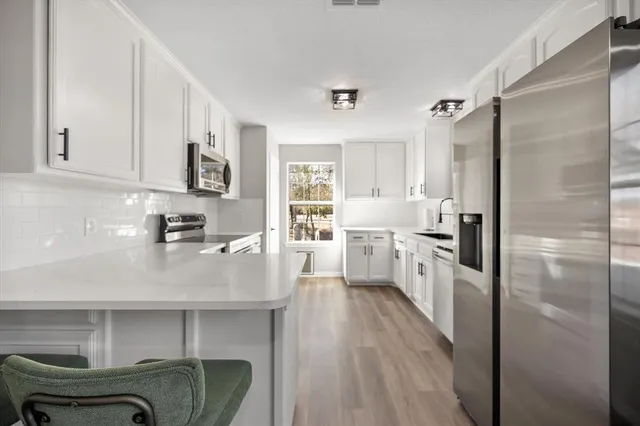 a kitchen with white cabinets and stainless steel appliances