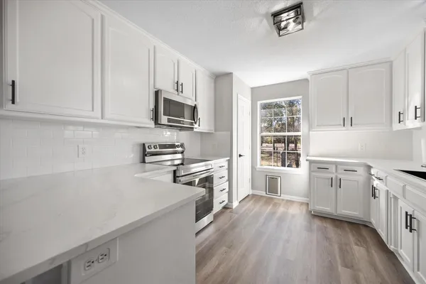 a kitchen with cabinets stainless steel appliances a sink and wooden floor