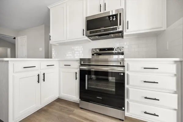 a kitchen with white cabinets and stainless steel appliances
