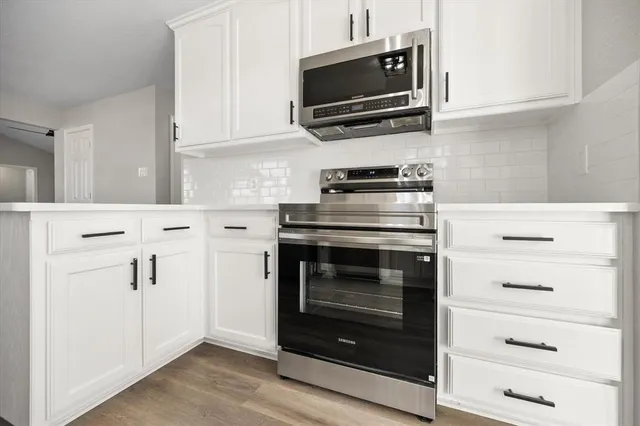 a kitchen with white cabinets and stainless steel appliances