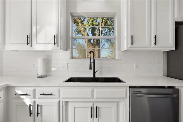 a kitchen with white cabinets and window