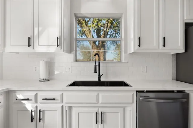 a kitchen with white cabinets and window