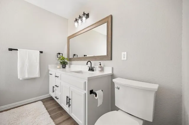 a bathroom with a toilet a sink a mirror a shower and vanity