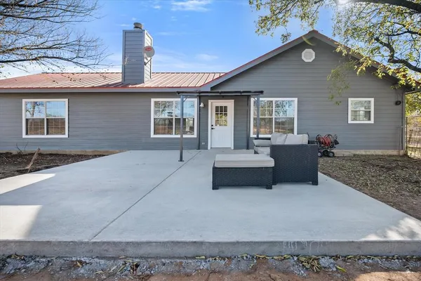 a front view of house with yard outdoor seating and covered with trees
