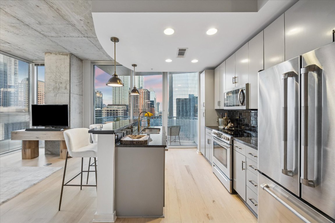 360 Nueces Street, Unit 1417 Austin, TX 78701 - Photo 6 of 40 a kitchen with stainless steel appliances kitchen island granite countertop a refrigerator and a stove top oven