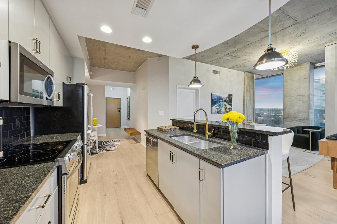 360 Nueces Street, Unit 1417 Austin, TX 78701 - Photo 7 of 40 a kitchen with stainless steel appliances granite countertop a sink a stove and a wooden cabinets