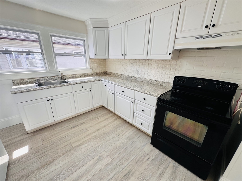 35-37 Suffolk Street Springfield, MA 01109 - Photo 12 of 17 a kitchen with granite countertop white cabinets and black appliances