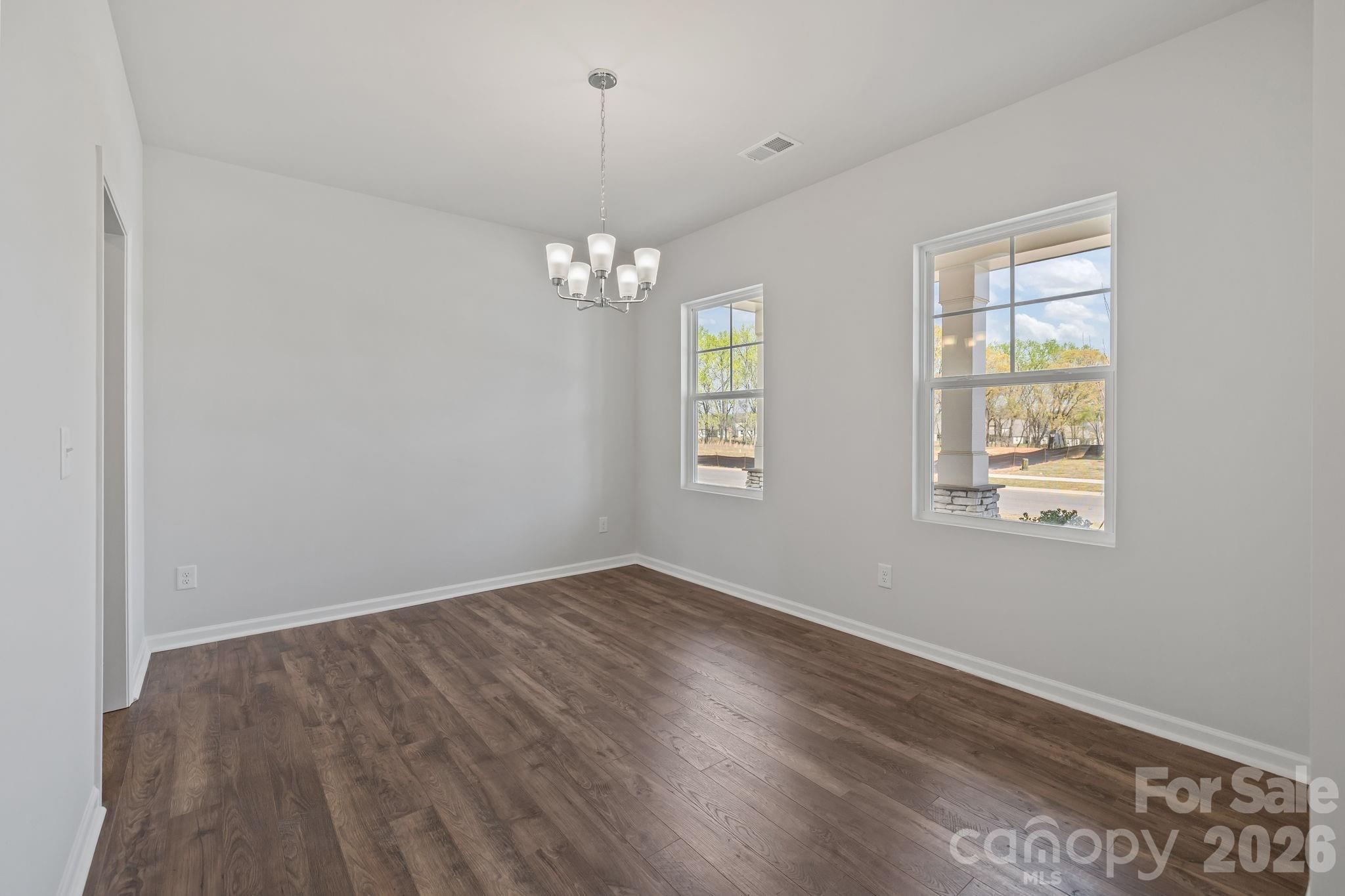 454 Brick House Road York, SC 29745 - Photo 9 of 35 an empty room with wooden floor chandelier and windows