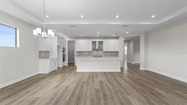 a large kitchen with a lot of kitchen island a sink dishwasher a kitchen island with wooden floor and chandelier