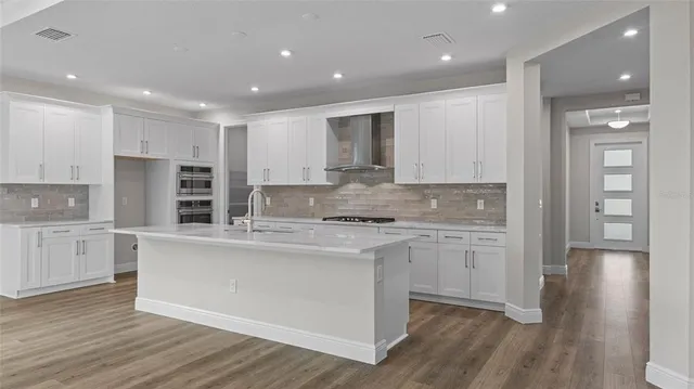 a large kitchen with cabinets wooden floor and stainless steel appliances