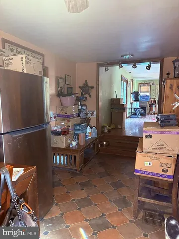 a living room with furniture a rug and a refrigerator