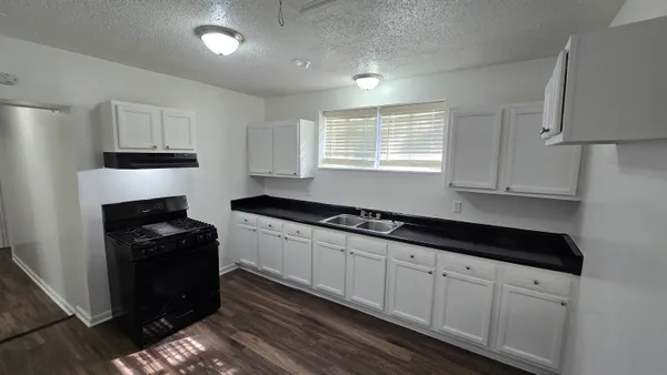 a kitchen with granite countertop white cabinets and a stove