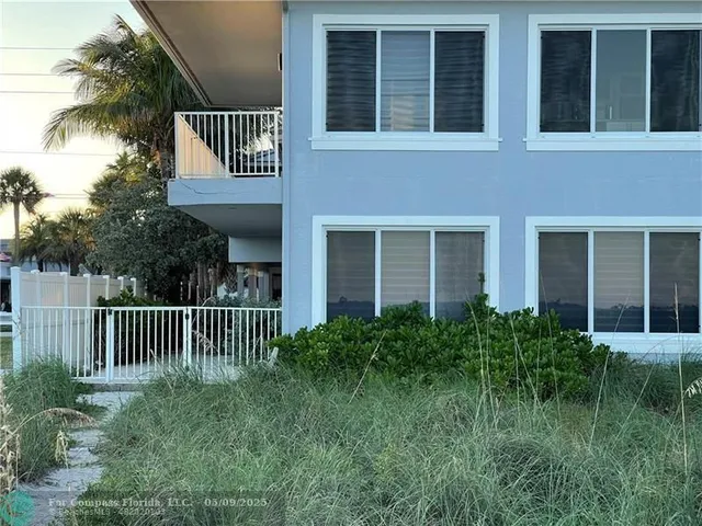 a view of a house with a small yard and flower plants