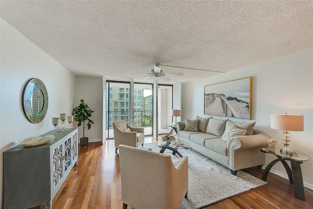 a living room with couches chairs and kitchen view with wooden floor