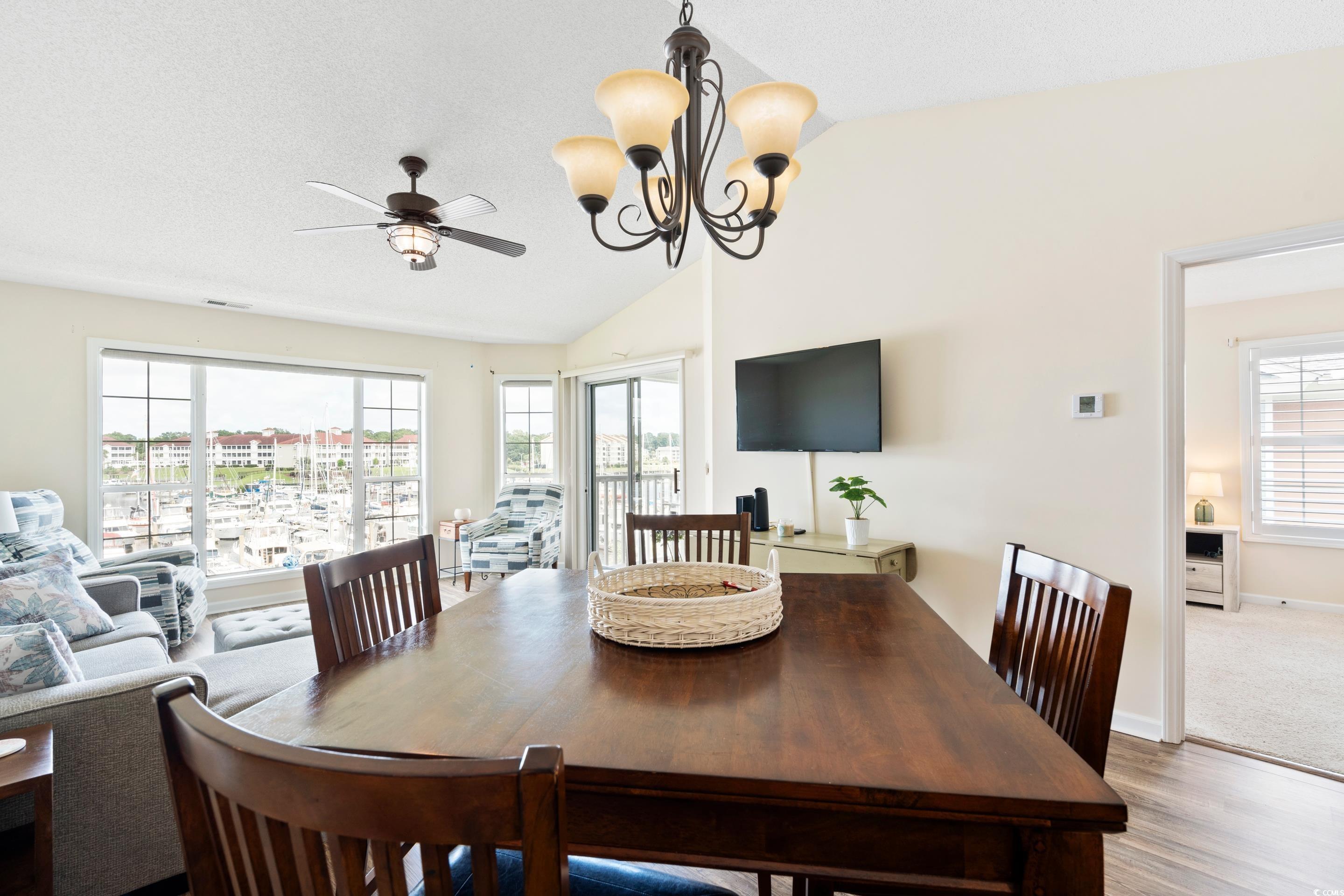 4629 Lightkeepers Way, Unit 6L Little River, SC 29566 - Photo 10 of 36 Dining area with lofted ceiling, a chandelier, wood finished floors, a ceiling fan, and a textured ceiling