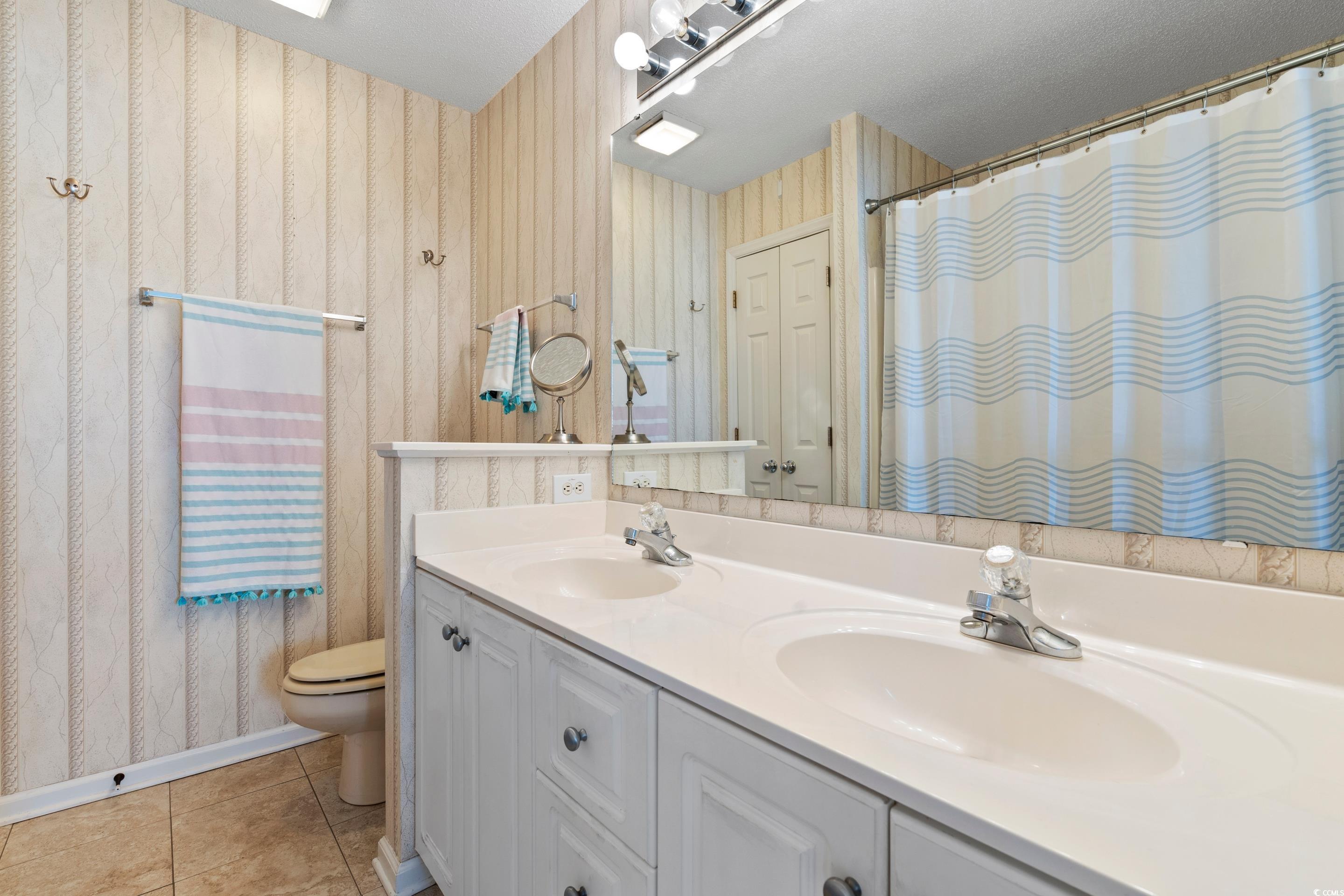 4629 Lightkeepers Way, Unit 6L Little River, SC 29566 - Photo 20 of 36 Full bath with light tile patterned flooring, double vanity, wallpapered walls, and a shower with curtain