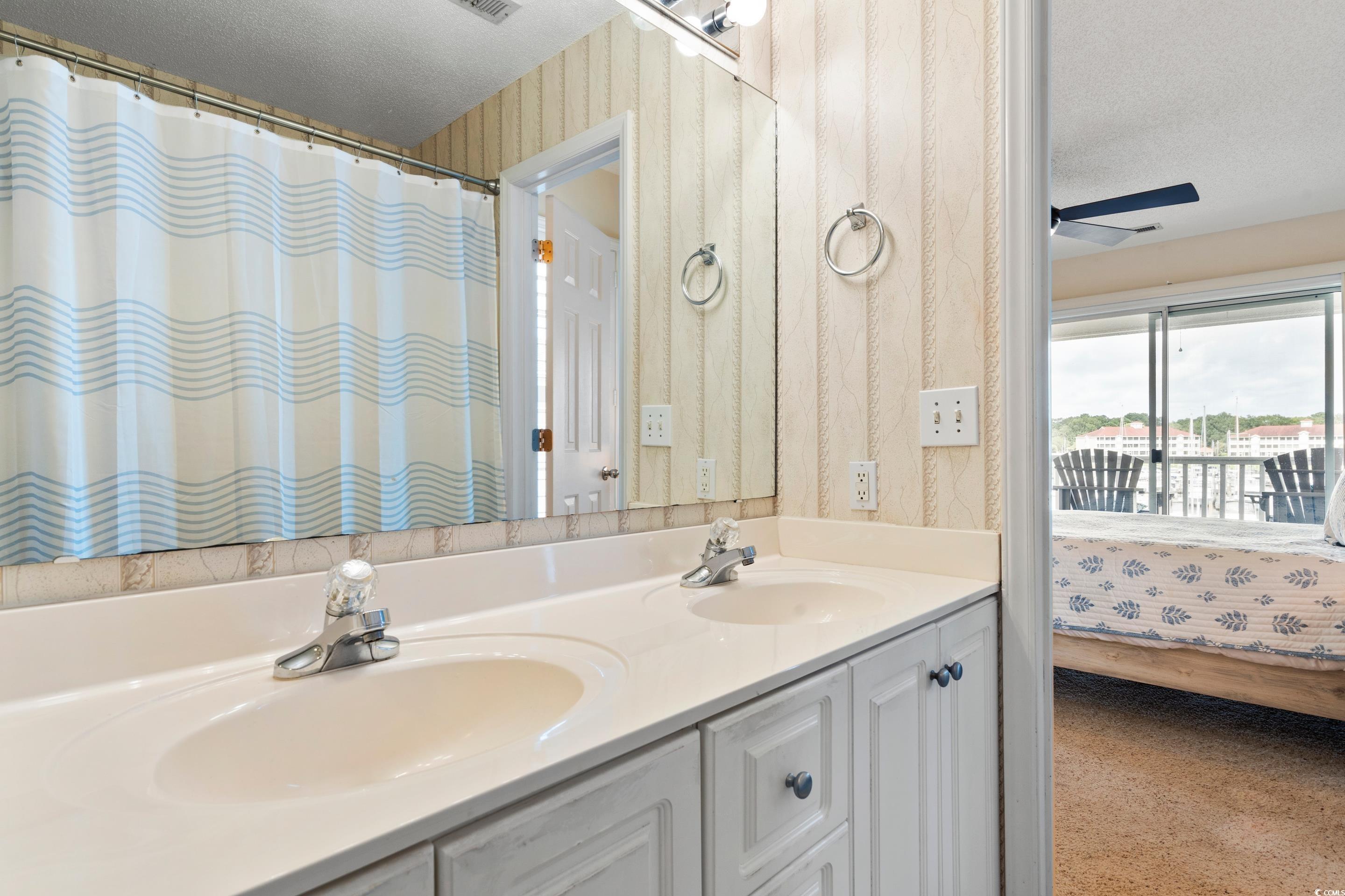 4629 Lightkeepers Way, Unit 6L Little River, SC 29566 - Photo 21 of 36 Ensuite bathroom with wallpapered walls, a textured ceiling, double vanity, a ceiling fan, and a shower with shower curtain