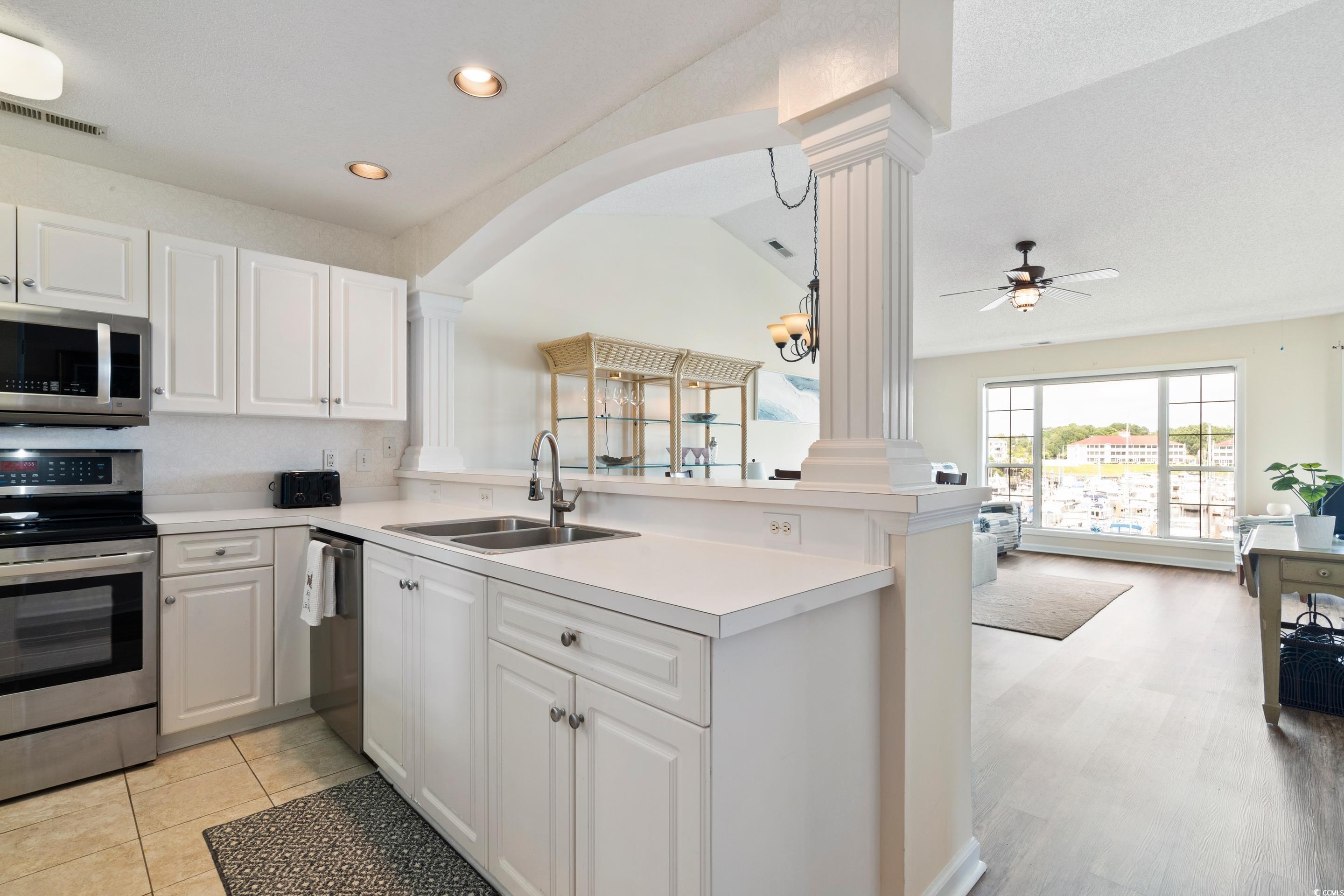 4629 Lightkeepers Way, Unit 6L Little River, SC 29566 - Photo 36 of 36 Kitchen featuring appliances with stainless steel finishes, white cabinetry, light countertops, a peninsula, and open floor plan