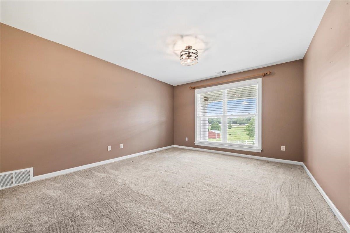 740 Frazier Road Rossville, TN 38066 - Photo 21 of 40 Carpeted interior room featuring a large window with horizontal blinds, a ceiling-mounted light fixture, warm-toned wall paint, and white trim