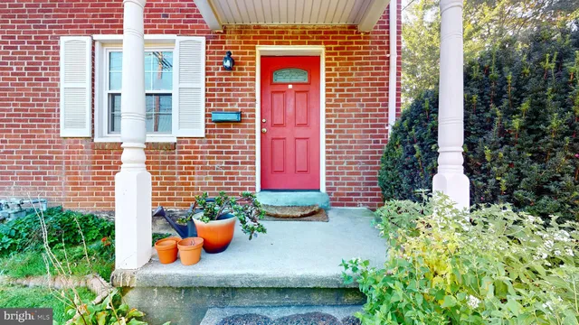 a view of a door of the house with chairs and potted plants
