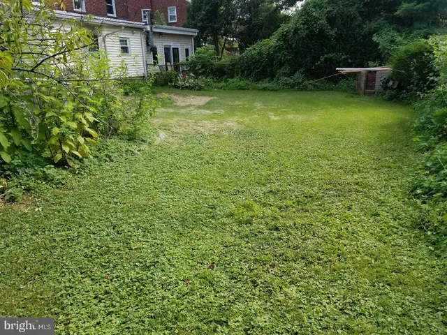 a view of a house with a big yard and large trees