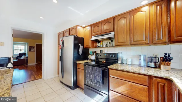 a kitchen with stainless steel appliances granite countertop a refrigerator a stove and a sink
