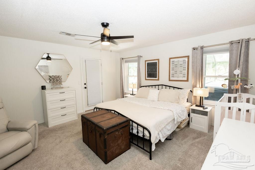 3059 Cobblestone Drive Pace, FL 32571 - Photo 22 of 45 a spacious bedroom with a bed a couch and large window