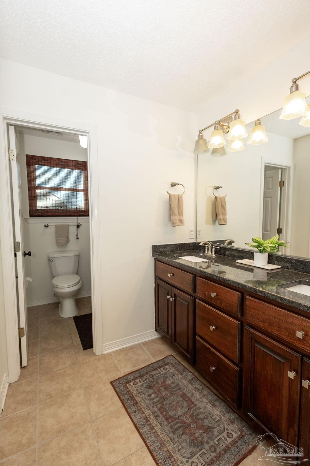3059 Cobblestone Drive Pace, FL 32571 - Photo 30 of 45 a bathroom with a granite countertop sink a toilet and a mirror