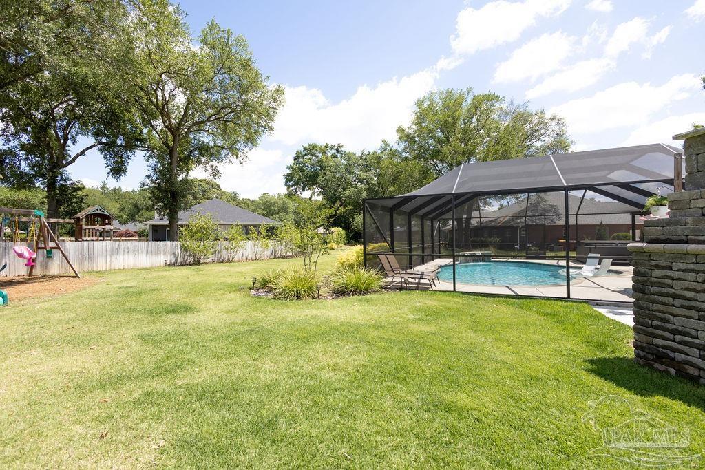 3059 Cobblestone Drive Pace, FL 32571 - Photo 37 of 45 a view of a swimming pool with lawn chairs under an umbrella