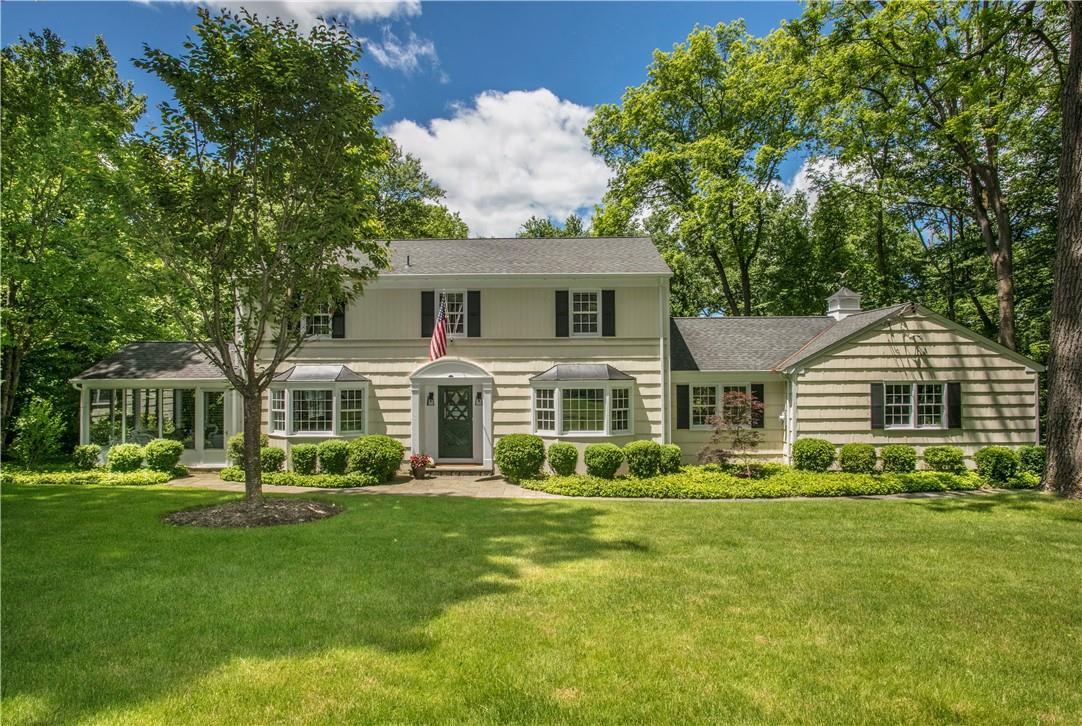 a front view of a house with a garden and trees